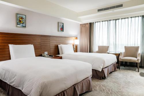 a hotel room with two beds and a chair at Arsma Hotel in Hualien City