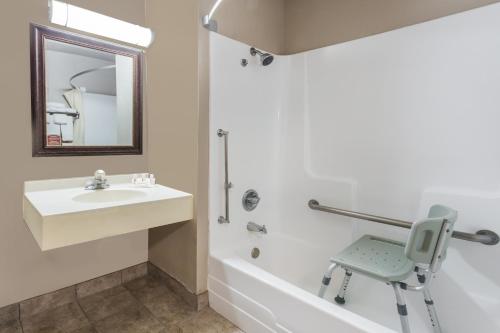 Un baño con un lavabo y una silla junto a una bañera. en Deluxe Inn Willows On I-5, en Willows
