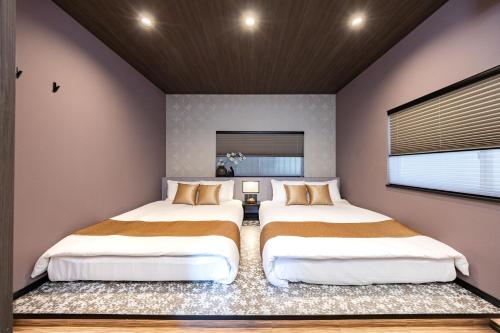 two beds in a room with two windows at JAPAVISTA Hinata in Osaka
