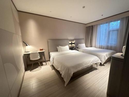 a hotel room with two beds and a desk and a window at Hanting Hotel Beijing Temple of Heaven in Beijing