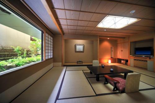 a room with a table and chairs and a window at Senkeien Tsukioka Hotel in Kaminoyama