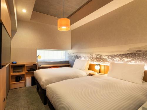 a hotel room with two beds and a window at Granbell Hotel Otaru in Otaru