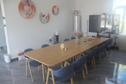 Una sala de conferencias con una gran mesa y sillas de madera. en Huaxiangli, 