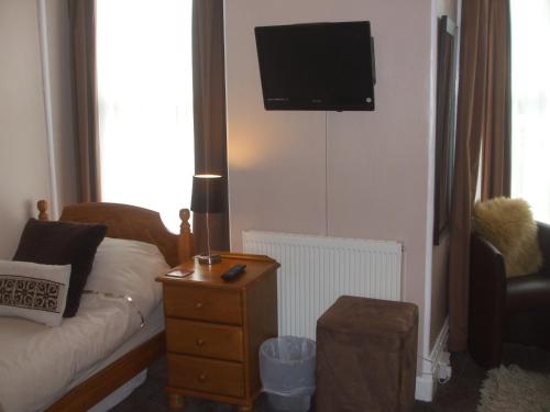 a living room with a couch and a tv on the wall at Chiverton House Guest Accommodation in Penzance