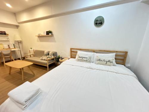 a bedroom with a large white bed and a chair at Secret Muji Vintage Building ห้องลับมูจิในตึกวินเทจ in Ban Song Hong