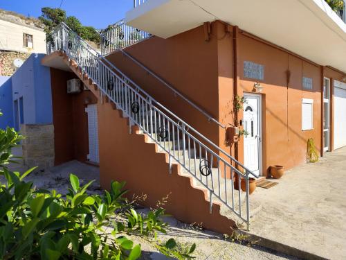 an orange building with a staircase next to a door at Despoinas House in Plátanos