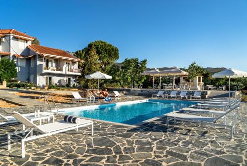 a pool at a resort with lounge chairs and umbrellas at Villa Eliza in Skala