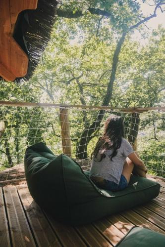 a girl sitting on a bean bag chair on a deck at La Cabanoun, cabane perchée vue lac in Coudures