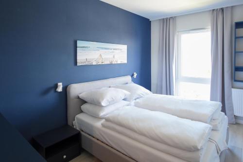1 dormitorio con 2 almohadas blancas y pared azul en VacationClub - Let's Sea Baltic Park Apartament F96, en Gąski