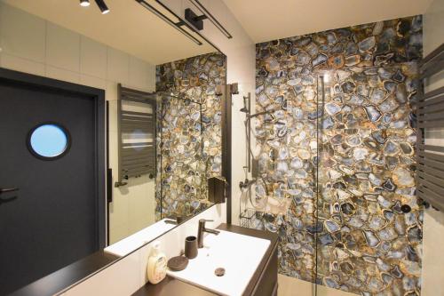 baño con lavabo y pared de mosaico en VacationClub - Let's Sea Baltic Park Apartament F96, en Gąski