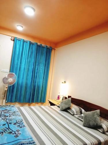 a bedroom with a large bed with blue curtains at Arara ibt homestay in Cherrapunji
