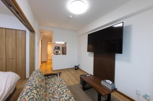 a hotel room with a couch and a flat screen tv at Tomattoco KASUMI in Yamagata