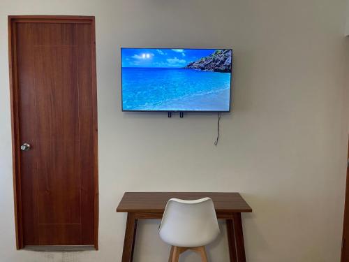 a flat screen tv on a wall with a table and a chair at Casa Lú in Santa Cruz Huatulco