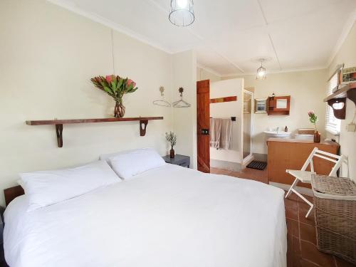 a bedroom with a white bed and a bathroom at Plaas Wegbreek in Barrydale
