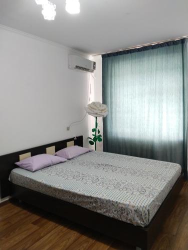 a bedroom with a bed with purple pillows and a window at Комфортная квартира для гостей города in Qyzylorda