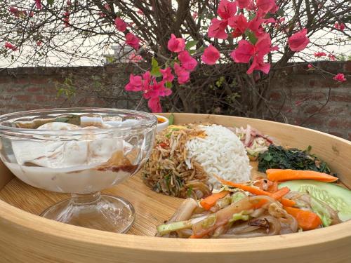 a wooden bowl of food with a bowl of salad and a drink at Lumbini Five Elements Hotel in Lumbini