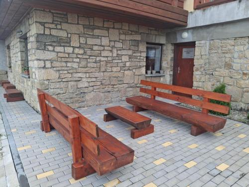two wooden benches sitting in front of a building at Rodinné chaty MORAVANPARK - Ubytování v srdci Valašska in Podkopná Lhota