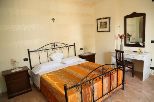 a bedroom with a bed and a desk and a mirror at Villa Manno in Barcellona-Pozzo di Gotto