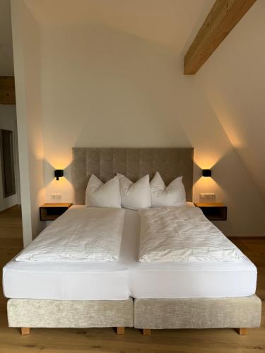 a bedroom with a white bed with two lamps at Seehotel Lilly in Strobl