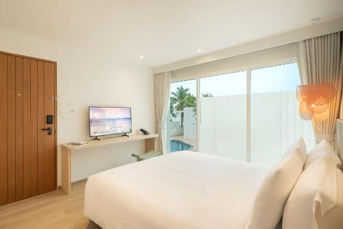 a bedroom with a large bed and a television at U Hua Hin in Cha Am