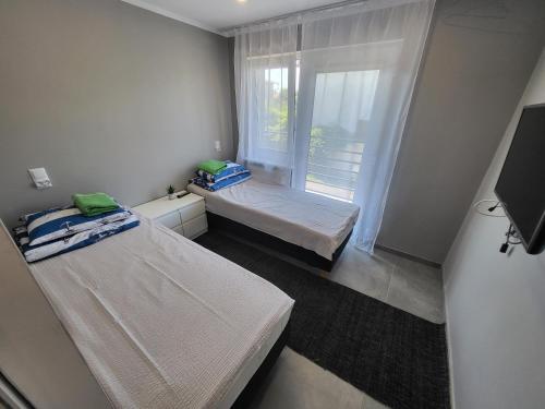 a small room with two beds and a window at Apartamenty Kacper Grzybowo in Grzybowo