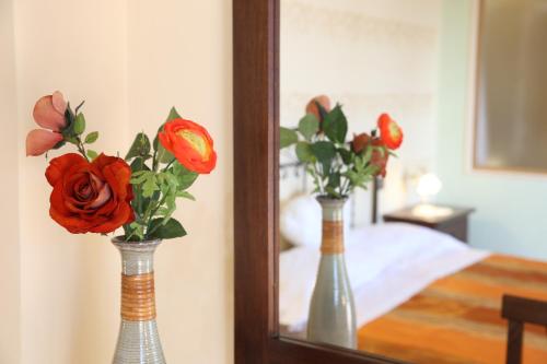 two vases with flowers in front of a mirror at Villa Manno in Barcellona-Pozzo di Gotto