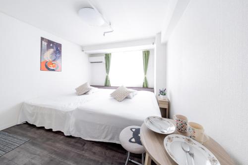 a bedroom with a white bed and a table at Yoshidokulnn3 Near World Expo USJOceanarium History Museum Umeda Namba Shisaibashibeside吉德旅館3近世博会USJ海洋館历史博物馆难波梅田心斋桥商业街斜对面 in Osaka