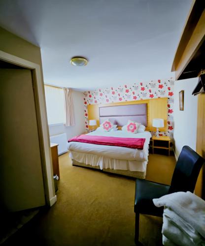 a bedroom with a bed with pink sheets and pink pillows at Station Hotel Portsoy in Portsoy