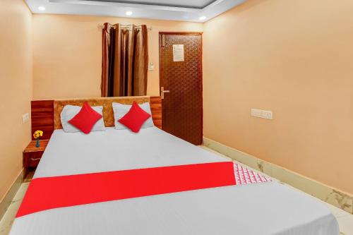a bedroom with a bed with red and white pillows at Hotel O Ashirwad Charbagh Bus Station in Lucknow