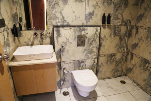 a bathroom with a toilet and a sink at ROOTS A Unit of Coastal Dine Restaurant & Lodging in Bengaluru