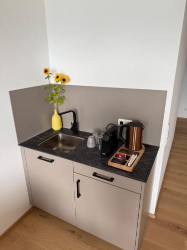 una pequeña cocina con fregadero y un jarrón de flores en Seehotel Lilly, en Strobl