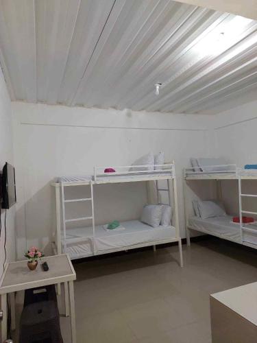 a room with three white bunk beds in a room at RedDoorz at Wyns Hotel in Silañgang Mayao