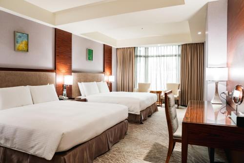 a hotel room with two beds and a desk at Arsma Hotel in Hualien City