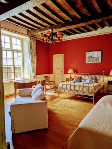 a bedroom with red walls and two beds and a table at Domaine de Launay blot in Baguer-Morvan
