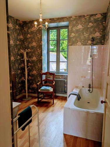 a bathroom with a tub and a chair and a window at Domaine de Launay blot in Baguer-Morvan