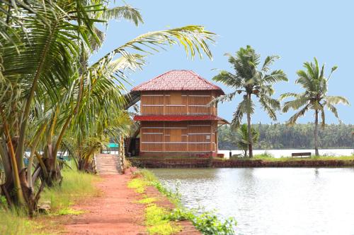 a building next to a body of water with palm trees at The Oyster Opera in Trikarpur