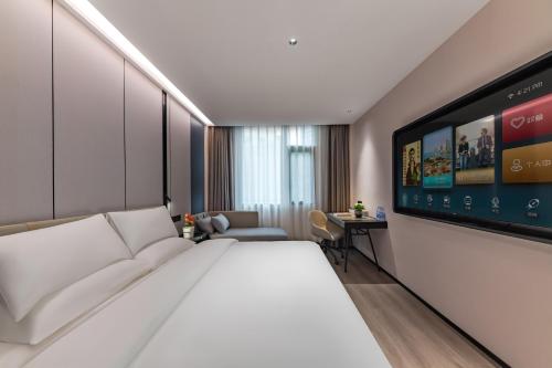 a bedroom with a large white bed and a tv at Urna Hotel Xiamen Railway Station Lianhua Road Subway Station Branch in Xiamen