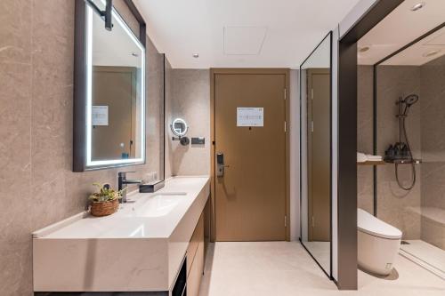a bathroom with two sinks and a shower and a toilet at Urna Hotel Xiamen Railway Station Lianhua Road Subway Station Branch in Xiamen