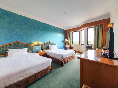 a hotel room with two beds and a desk at Parkview Hotel in Kampong Jerudong