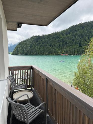 a balcony with two chairs and a view of a lake at Seehotel Lilly in Strobl