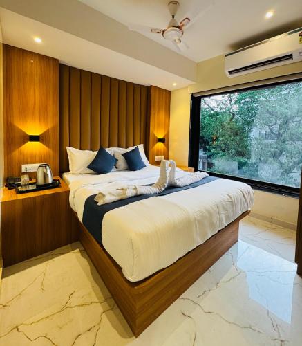 a bedroom with a large bed with a large window at Hotel Comfort Castle in Mumbai
