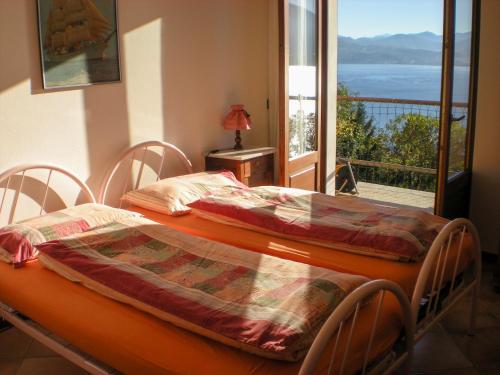 Dos camas en una habitación con vista a un balcón. en Casa Gardenia, en Oggebbio
