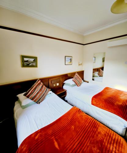 a hotel room with two beds with red and white sheets at Station Hotel Portsoy in Portsoy