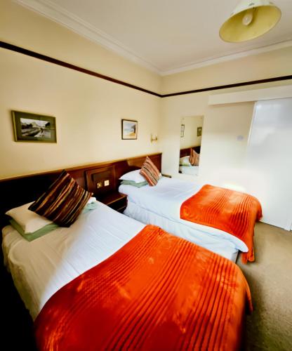 a hotel room with two beds with red and white sheets at Station Hotel Portsoy in Portsoy