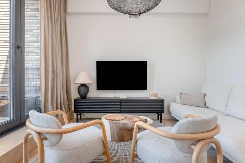 a living room with a couch and a tv at Modern Luxury Apartment in Nida I 2BR Apartmen I Terrace I Cᴏʜᴏsᴛ in Nida