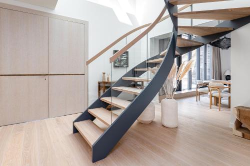a spiral staircase in a living room with a table at Modern Luxury Apartment in Nida I 2BR Apartmen I Terrace I Cᴏʜᴏsᴛ in Nida