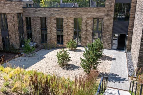 a courtyard with trees in front of a brick building at Modern Luxury Apartment in Nida I 2BR Apartmen I Terrace I Cᴏʜᴏsᴛ in Nida