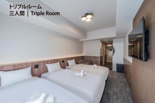 two beds in a hotel room with a tv at Apartment Hotel 11 Nippombashi in Osaka