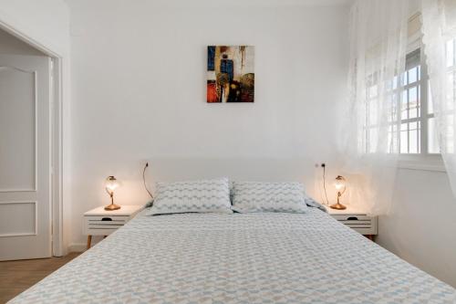 a white bedroom with a bed and two lamps at Casa Mayo con piscina privada in Conil de la Frontera