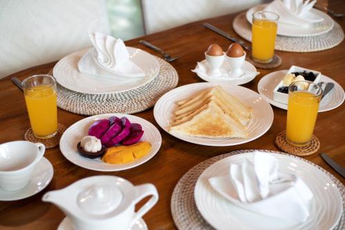 un tavolo in legno con piatti per la colazione e succo d'arancia di Villa Mannao by Villa Finder a Kerobokan